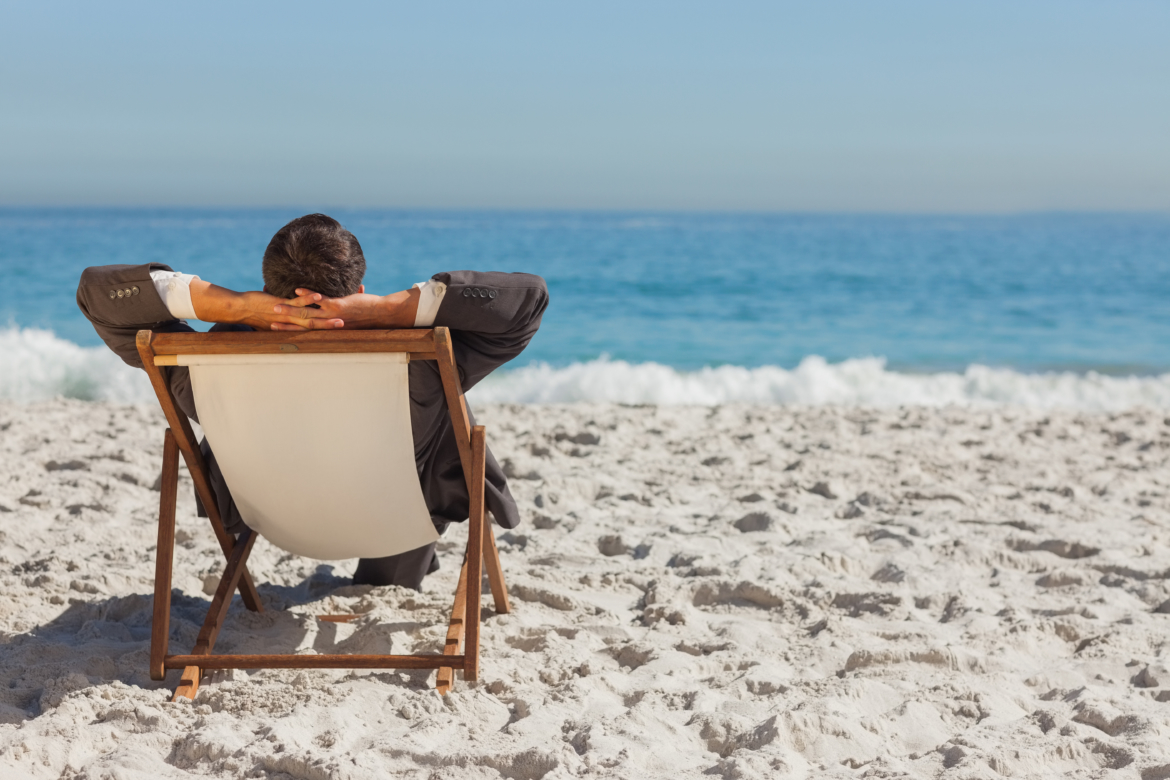 Young businessman relaxing on his sun lounger on the beach