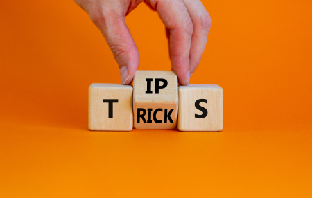 Tips and tricks symbol. Businessman turn the wooden cube and changes the word 'tips' on 'tricks'. Beautiful orange background. Business and tips and tricks concept, copy space.